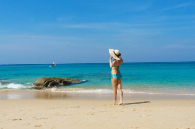 A beautiful woman in a swimsuit posing on a Thai beach at summer. Holiday, vacation, traveling and resort concept.