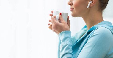 Pencerenin önünde duran ve ona bakan genç bir kadının yakın plan portresi. Kız evde, oturma odasında. Sabah konsepti.