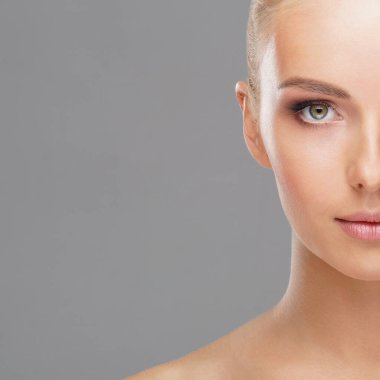 Genç ve sağlıklı kız gri arka plan üzerinde güzel yüzü. Cilt Bakımı, kozmetik ve yüz kavramı kaldırma.