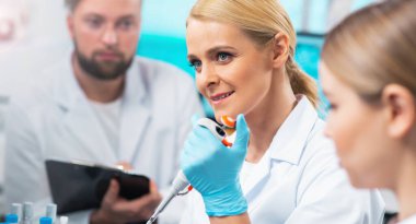 Team of professional scientists working on a vaccine in a modern scientific research laboratory. Genetic engineer workplace. Laboratory tools: microscope, test tubes, equipment. Future technology