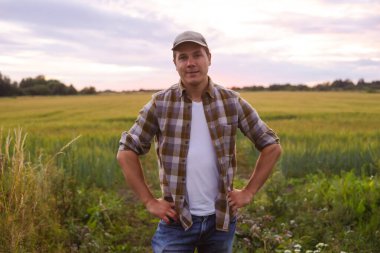 Günbatımı tarımının önündeki çiftçi. Kırsal kesimde bir adam. Kır hayatı, gıda üretimi, tarım ve kırsal yaşam tarzı kavramı.