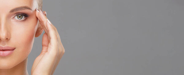 Beautiful face of young and healthy girl over grey background. Skin care, cosmetics and face lifting concept.