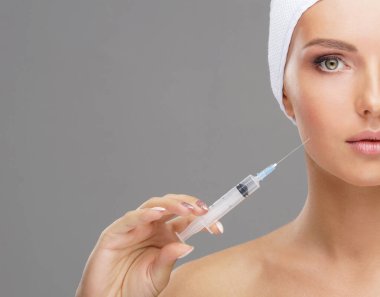 Genç bir kadının yüzüne güzellik aşısı. Estetik ameliyat, cilt gerdirme ve estetik tıp konsepti.