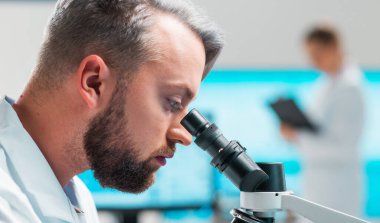 Profesyonel bilim adamları modern bir bilimsel araştırma laboratuvarında bir aşı üzerinde çalışıyorlar. Genetik mühendisliği işyeri. Gelecekteki teknoloji ve bilim konsepti.