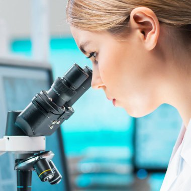Professional female scientist is working on a vaccine in a modern scientific research laboratory. Laboratory tools: microscope, test tubes, equipment. Future technology, healthcare and science concept
