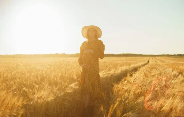 日没の光線で妊娠中の女性 美しい若い女の子が子供の誕生を期待して畑を歩いています 幸福の概念 — ストック写真