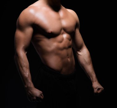Siyah arka plan üzerinde güçlü, formda ve sporcu bir vücut geliştirici. Spor ve spor konsepti