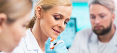 Modern bir bilimsel araştırma laboratuvarında aşı üzerinde çalışan profesyonel bilim adamlarından oluşan bir ekip. Genetik mühendisliği işyeri. Laboratuvar aletleri: mikroskop, test tüpleri, ekipmanlar. Gelecek teknolojisi