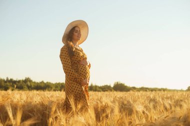 Günbatımında hamile bir kadın. Güzel bir genç kız bir çocuğun doğmasını umarak tarlada yürüyor. Annelik, hamilelik ve mutluluk kavramı..