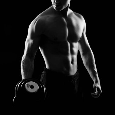 Siyah arka plan üzerinde güçlü, formda ve sporcu bir vücut geliştirici. Spor ve spor konsepti