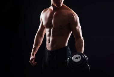 Siyah arka plan üzerinde güçlü, formda ve sporcu bir vücut geliştirici. Spor ve spor konsepti