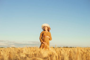 Günbatımında hamile bir kadın. Güzel bir genç kız bir çocuğun doğmasını umarak tarlada yürüyor. Annelik, hamilelik ve mutluluk kavramı..