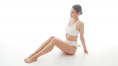 İzole edilmiş beyaz arka planda beyaz iç çamaşırlı güzel bir kadın. Stüdyoda mayo giymiş sağlıklı bir genç kızın videosu. Sağlık ve cilt bakımı, sağlık, diyet ve kozmetik kavramı.