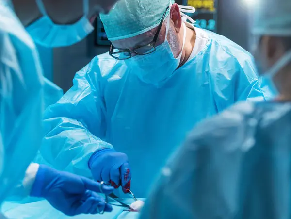 多样化的专业医生团队使用高科技设备和技术 在现代手术室进行外科手术 医生们正在努力抢救医院里的病人 — 图库照片