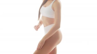 İzole edilmiş beyaz arka planda beyaz iç çamaşırlı güzel bir kadın. Mayo giymiş sağlıklı genç bir kızın yakın çekim videosu. Sağlık ve cilt bakımı, sağlık, diyet ve kozmetik kavramı.