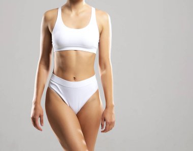 Beyaz arka planda beyaz mayo giyen genç, fit ve güzel bir kadın. Sağlık, diyet, spor ve spor konsepti.