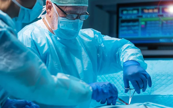 多样化的专业医生团队使用高科技设备和技术 在现代手术室进行外科手术 医生们正在努力抢救医院里的病人 图库照片