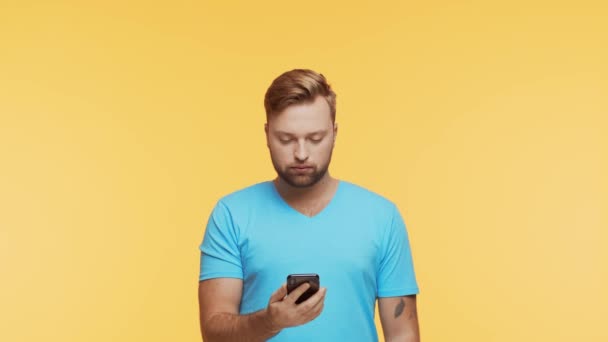 活気に満ちた背景の上にスマートフォンで表現若い男 ハンサムな人のスタジオ肖像画 — ストック動画