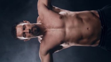 Siyah arka planda formda ve sportif vücut geliştirici. Halter kullanarak vücut geliştirici eğitimi. Spor ve spor kavramları. Dikey video.