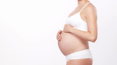 Genç, mutlu ve sağlıklı hamile bir kadın beyaz arka planda. Stüdyo videosu. Bebek beklentisi, hamilelik ve annelik kavramı.