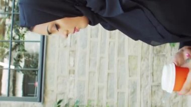 Genç ve kendinden emin, tesettürlü Müslüman bir iş kadınının portresi. Orta Doğulu ofis çalışanı veya iş kadını şehirde açık havada çalışıyor. Dikey video. Şirket ve finansal konsept.