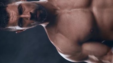 Siyah arka planda formda ve sportif vücut geliştirici. Halter kullanarak vücut geliştirici eğitimi. Spor ve spor kavramları. Dikey video.