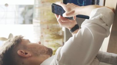 Bir kafede oturan ve çalışan bir iş adamı. Bilgisayar ve cihaz kullanan bir adam. İş ve girişimcilik kavramı kavramı. Dikey video.