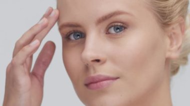 Cilt bakımı kremi süren genç, güzel ve doğal sarışın kadının stüdyo portresi. Yüz gerdirme, kozmetik ve makyaj konsepti.