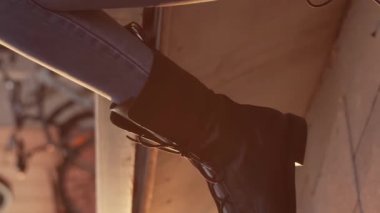 Genç çekici iş kadını dışarıda bankta oturuyor ve akıllı telefon kullanıyor. Gün batımı ışığı. Dikey video.