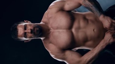 Siyah arka planda formda ve sportif vücut geliştirici. Halter kullanarak vücut geliştirici eğitimi. Spor ve spor kavramları. Dikey video.