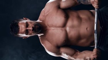 Siyah arka planda formda ve sportif vücut geliştirici. Halter kullanarak vücut geliştirici eğitimi. Spor ve spor kavramları. Dikey video.