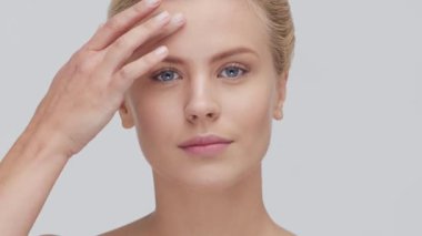 Cilt bakımı kremi süren genç, güzel ve doğal sarışın kadının stüdyo portresi. Yüz gerdirme, kozmetik ve makyaj konsepti.