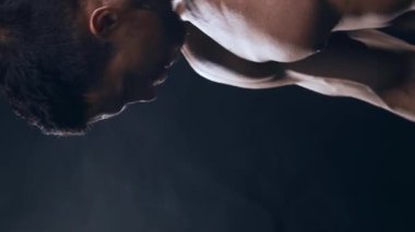 Siyah arka planda formda ve sportif vücut geliştirici. Halter kullanarak vücut geliştirici eğitimi. Spor ve spor kavramları. Dikey video.
