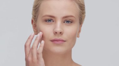 Cilt bakımı kremi süren genç, güzel ve doğal sarışın kadının stüdyo portresi. Yüz gerdirme, kozmetik ve makyaj konsepti.