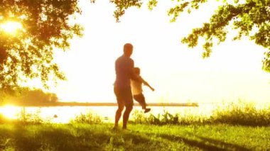 Deniz kenarında mutlu bir aile. Kırsal kesimde tarla ve ağaçlar. Gün batımının ya da güneşin sıcacık renkleri. Sevgi dolu ebeveynler ve güzel çocuklar. Aşk ve ebeveynlik kavramı.