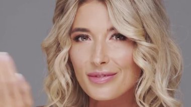 Gri arka planda genç ve güzel sarışın kadının stüdyo portresi. Cilt bakımı ve sağlık kavramı.