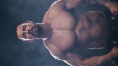 Siyah arka planda formda ve sportif vücut geliştirici. Halter kullanarak vücut geliştirici eğitimi. Spor ve spor kavramları. Dikey video.