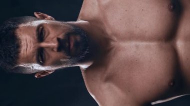 Siyah arka planda formda ve sportif vücut geliştirici. Halter kullanarak vücut geliştirici eğitimi. Spor ve spor kavramları. Dikey video.