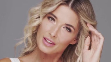 Gri arka planda genç ve güzel sarışın kadının stüdyo portresi. Cilt bakımı ve sağlık kavramı.