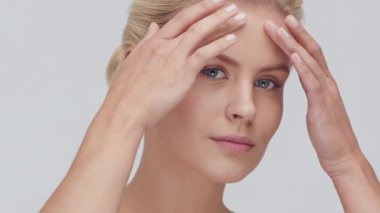 Cilt bakımı kremi süren genç, güzel ve doğal sarışın kadının stüdyo portresi. Yüz gerdirme, kozmetik ve makyaj konsepti.