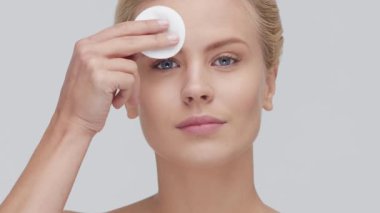 Cilt bakımı kremi süren genç, güzel ve doğal sarışın kadının stüdyo portresi. Yüz gerdirme, kozmetik ve makyaj konsepti.