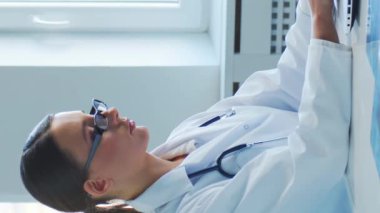 Hastane ofisinde çalışan profesyonel tıp doktorları bilgisayar araştırması yapıyor. Tıp, sağlık ve teknoloji kavramı. Dikey video.