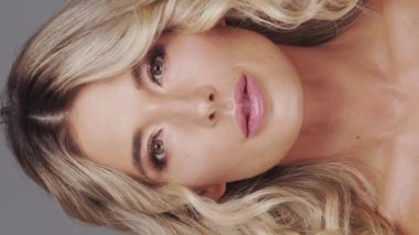 Gri arka planda genç ve güzel sarışın kadının stüdyo portresi. Cilt bakımı ve sağlık kavramı.