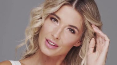 Gri arka planda genç ve güzel sarışın kadının stüdyo portresi. Cilt bakımı ve sağlık kavramı.