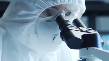 Laboratuvar ekipmanları, mikroskoplar ve test tüpleri kullanarak araştırma laboratuarında çalışan koruyucu giysi ve maskeler giyen bilim adamları. Tıp, sağlık ve teknoloji kavramı.