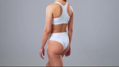 Genç, fit ve beyaz mayo giymiş güzel sarışın kadın gri arka planda poz veriyor. Sağlık, diyet, spor ve spor kavramı.