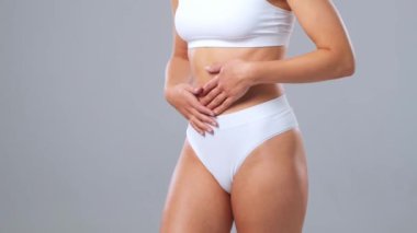 Genç, fit ve beyaz mayo giymiş güzel sarışın kadın gri arka planda poz veriyor. Sağlık, diyet, spor ve spor kavramı.