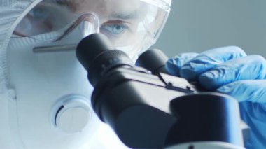 Laboratuvar ekipmanları, mikroskoplar, test tüpleri kullanarak araştırma laboratuarında çalışan koruma giysisi ve maskesi giyen bilim adamları. Tıp, sağlık ve teknoloji kavramı.