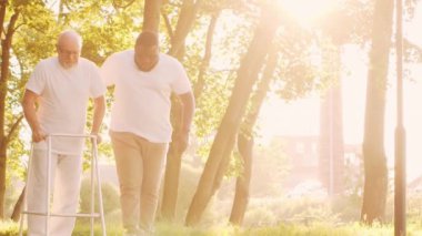 Afro-Amerikalı bakıcı ve yaşlı adam. Bakımevindeki profesyonel hemşire ve hastası. Yardım, rehabilitasyon ve sağlık hizmetleri kavramı.