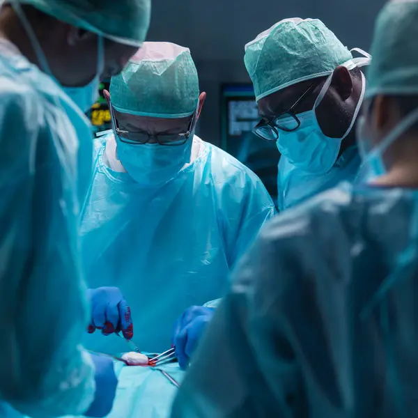 多样化的专业医生团队使用高科技设备和技术 在现代手术室进行外科手术 医生们正在努力抢救医院里的病人 图库图片